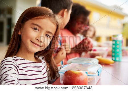 Girl at elementary school lunch table smiling to camera