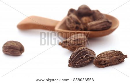 Black Cardamom In A Wooden Spoon Over White
