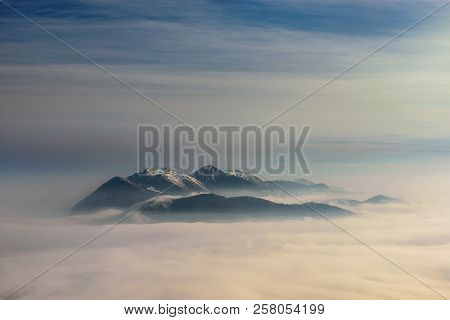 Wank Mountain View During Winter Morning. Dramatic Cloudy Sky. Typical Foggy Atmosphere. Snowy Peaks