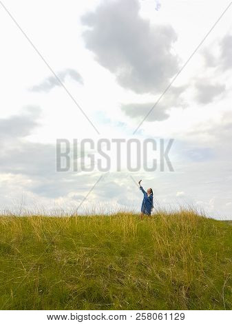 A Young Woman With Red Hair And A Blue Denim Dress Is In The Mountains Outside The City And Is Tryin