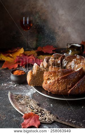Bundt Cake With Saffron And Rum Covered With White Glaze On Rustic Background With Autumn Decoration