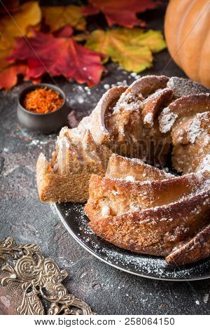 Bundt Cake With Saffron And Rum Covered With White Glaze On Rustic Background With Autumn Decoration