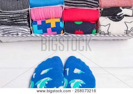 Box With Different Colorful Socks. Feet Selfie And A Socks Organizer On A White Background. Top View