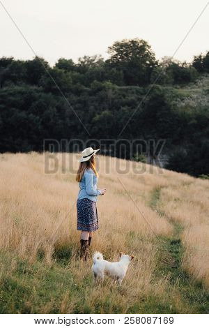 Girl In A Hat Playing With A Dog In The Field At Sunset Sun