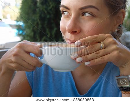 Young Blond Female Hacing Coffee, Sitting In Street Cafeteria. Outdoor Closeup
