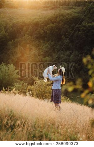 Girl In A Hat Playing With A Dog In The Field At Sunset Sun
