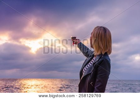 Girl Holding A Glass With Wine Uring The Sunset On The Sea