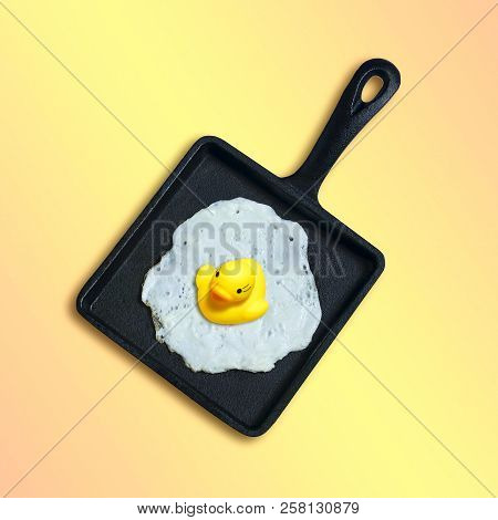 Square Cast-iron Frying Pan With Fried Eggs, Toy Duckling Instead Of Yolk. Artificial Objects That M
