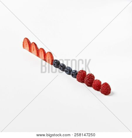 Macro Photo of Healthy Fresh Berries Breakfast Components or Food Ingredients Concept Isolated. Minimal Creative Layout with Organic Strowberries, Blueberries, Raspberries Lined Up in a Diagonal Row