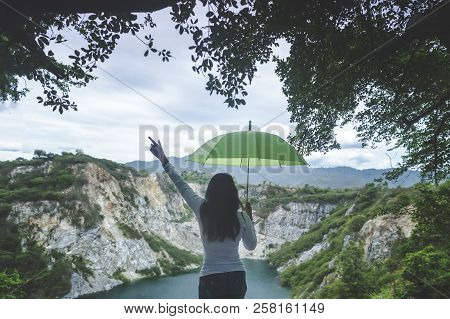 Hipster Young Girl With Green Umbella Enjoying Sunset On Peak Mountain. Tourist Traveler On Backgrou