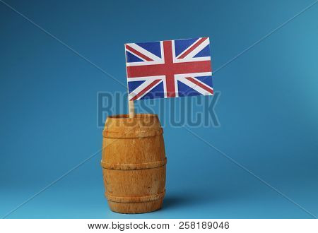 A Flag Of United Kingdom, Great Britain, On Wooden Stick In Wooden Barrel. Blue Background