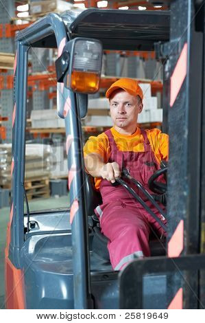 young cheerful warehouse worker driver in uniform driving forklift stacker loader