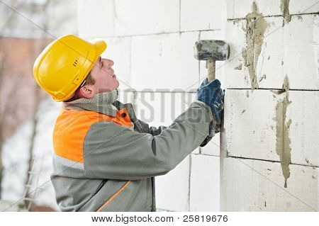 pedreiro de trabalhador de pedreiro de construção instalação do tijolo de silicato de cálcio por martelo batendo trabalho