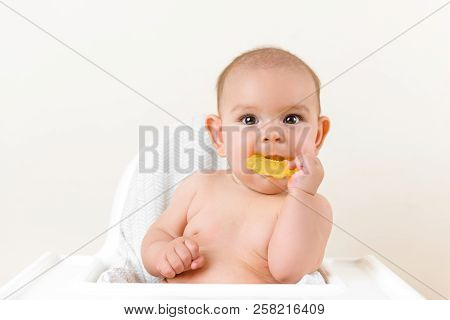Cute Baby Infant Kid Biting Sitting In Highchair And Chewing Yellow Eething Toy Copy Space Bright Mi