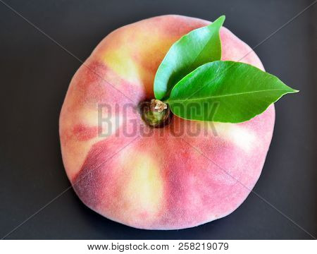 Chinese Flat Peach With Leaves On A Dark Background.donut Peach Also Known As Saturn Peach,paraguayo