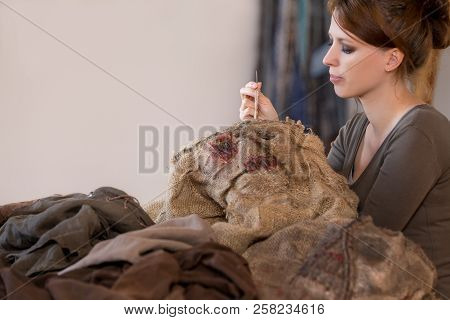 Woman Is Sewing A Scarecrow Mask And Costume For Carneval Or Halloween, Maybe A Prop For A Movie Or 