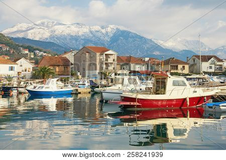 Winter Mediterranean Landscape. Fishing Boats In Harbor On Background Of Snowy Mountains. Montenegro