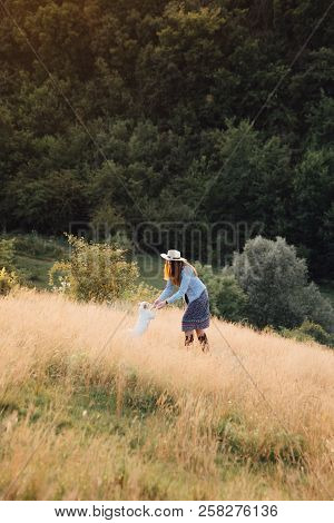 Girl In A Hat Playing With A Dog In The Field At Sunset Sun