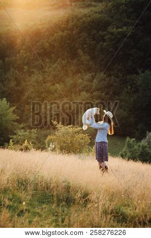 Girl In A Hat Playing With A Dog In The Field At Sunset Sun