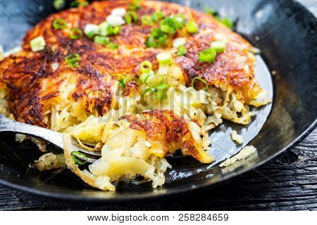 Traditional Swiss hash browns as side dish with leek as closeup in a frying pan 
