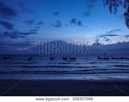 Evening Dusk Shot Of The Sea In The Blue Hour With Silohettes Of Boats.  A Summer Shot Taken In Thai