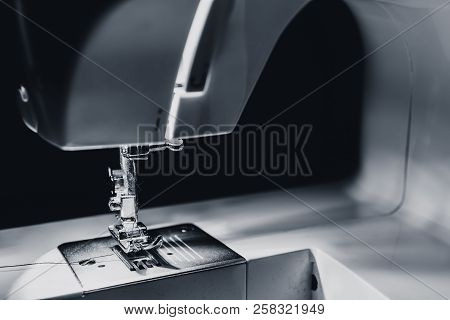 Modern Compact Electric Sewing Machine In The Evening. View Of Needle And Thread. Illumination From 