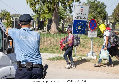 Tovarnik, Croatia - September 19, 2015: Croatian Police Officer Looking At Refugees Passing In Front