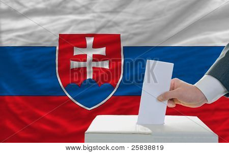 Człowiek głosowania w wyborach na Słowacji przed flagą
