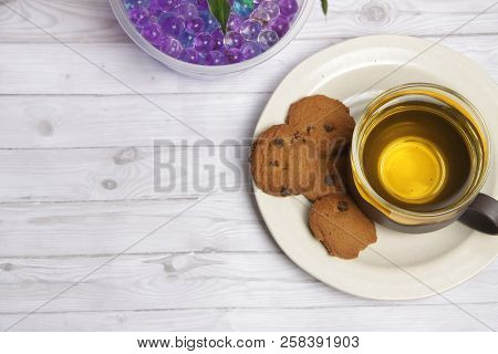 A Cup Of Green Tea With Choco Chips Cookies On White Wooden Table