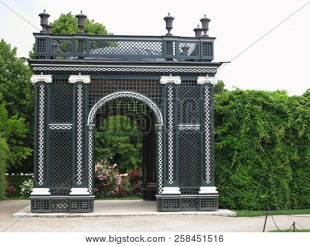 Abstract Black Garden Arbor, Flower Beds And Shorn Trees In A Well-kept Park