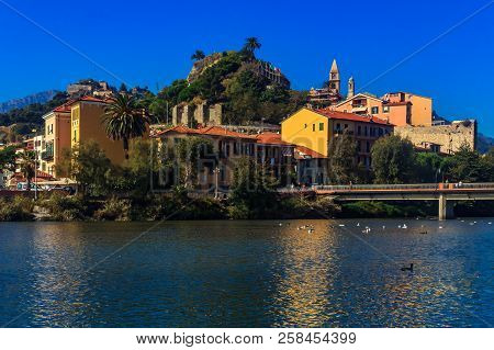 Colorful Old Buildings Perched Atop A Hill In The Medieval Town Of Vintimiglia In Italy, Just Across