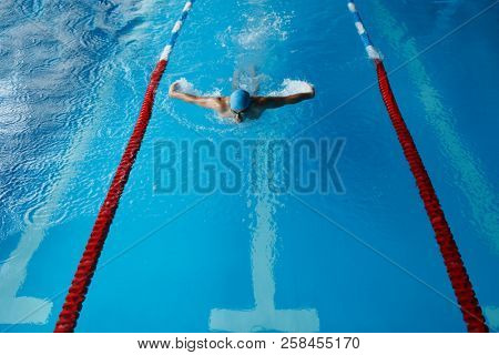 Photo of sports man in blue cap swimming in pool
