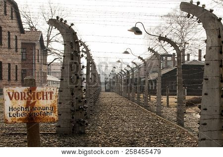 Auschwitz, Poland - March 30 2012 Melancholic View Through A Wired Electric Fence Of A Concentration