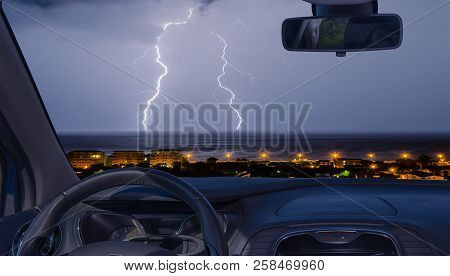 Looking Through A Car Windshield With View Of Lightning Storm Over The Sea