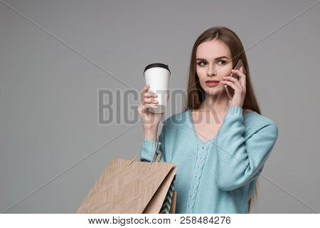 Girl In Aquamarine With Bags Drinking Coffee Talks By Smartphone
