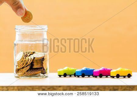 Investor Hand Hold A Coin With Save In Jar With Growing For Interest And Car Model On The Desk In Th