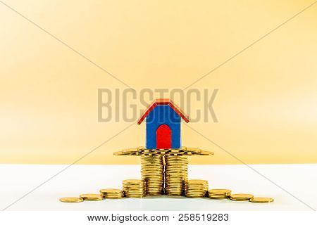 Home Model Put On The Stacked Gold Coin On Brown Background In The Office, Saving Money For Buy A Ne