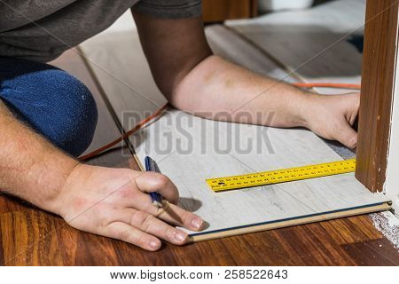 Construcion Worker Measuring Floor Panels Using Ruler And Pencil. Home Renovation Concept.