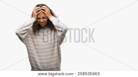 Beautiful young hispanic woman wearing stripes sweater suffering from headache desperate and stressed because pain and migraine. Hands on head.