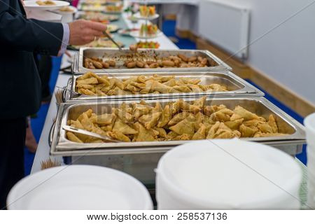 Feast. Table Full Of Food. Fried Rolls, Sousages And Plated. Arm With Spoon.