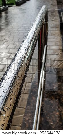 Metal Chrome-plated Handrail In The Drops Of Rain On A Cobblestone Sidewalk