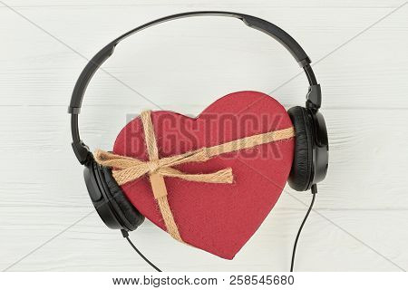 Headphones With Red Heart-shaped Gift Box. Black Headset And Gift Box In A Shape Of Heart Over White