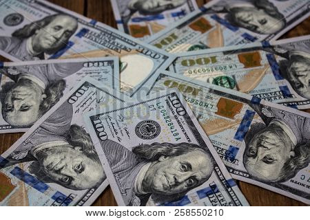 A Stack Of One Hundred Dollar Bils On Wooden Background