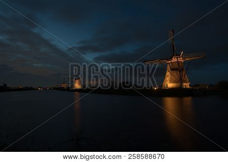 These Beautiful Windmills In Kinderdijk Are Illuminated With White Light At The Blue Hour