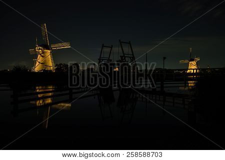 These Beautiful Windmills In Kinderdijk Are Illuminated With White Light At The Blue Hour