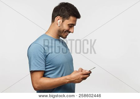 Side Portrait Of Handsome Man In Blue T Shirt, Isolated On Gray Background, Looking At Screen Of Sma