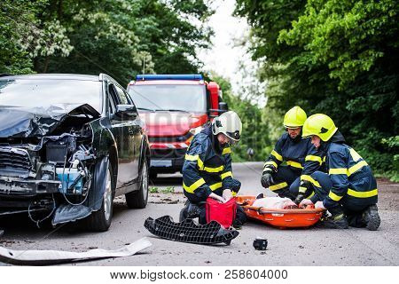 Firefighters Helping A Young Injured Woman After A Car Accident.