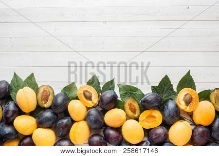 Fresh Plum And Apricot Berries With Leaves On A Light Table.