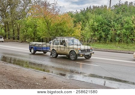 Krasnoyarsk, Russia - September 16, 2018: Vaz 2121 Niva Car With The Trailer Moves On The Country Ro