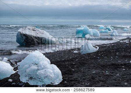 Pieces Of Glacier Ice At The Diamond Beach, Iceland, Near Jökullsárlón Glacier Lagoon, At A Misty Su
